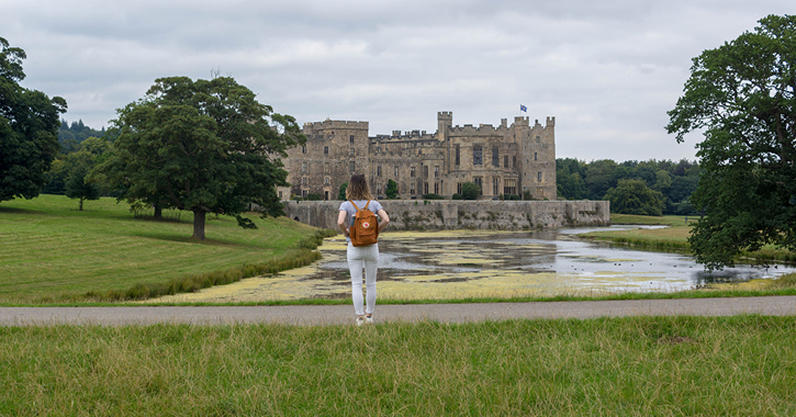 woman stood with back to camera looking at Raby Castle from the deer park